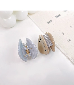 Close-up of mini acetate hair claws with cute dog faces and blue wavy edge design
