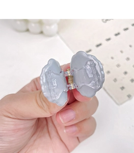 Close-up showing the opening mechanism of a mini gray-blue shell claw hair clip