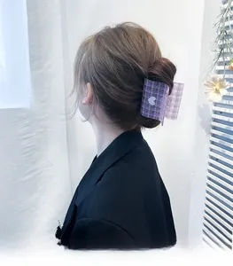 Detail of purple plaid claw clip with heart motif worn on a woman's hair in a neat bun