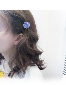 Detail view of mini purple cartoon puppy hair claw clip worn on wavy brown hair
