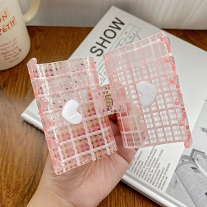 Pink checkered square hair claw clip with white heart details held over a wooden table