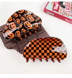Detail showing acetate hair claws with Halloween pumpkin face and checkered patterns