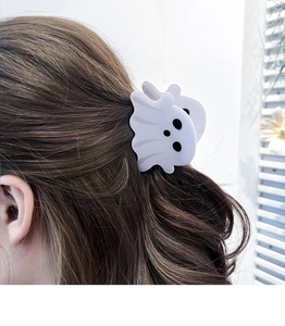 Détail d'une pince à cheveux fantôme violette pour Halloween sur cheveux bruns