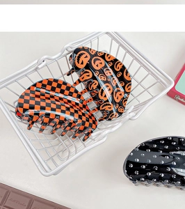 Detailed view of Halloween hair claws featuring pumpkin, skull, and checkered patterns
