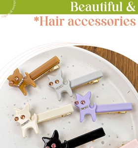 Détail de pinces à cheveux chat en acétate avec strass colorés dans un plat en céramique