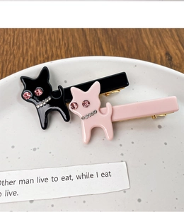 Gros plan de barrettes chat en acétate avec strass incrustés sur une assiette blanche
