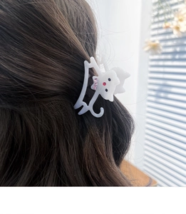 Détail d'une pince à cheveux chat blanche en acétate avec strass sur cheveux marron