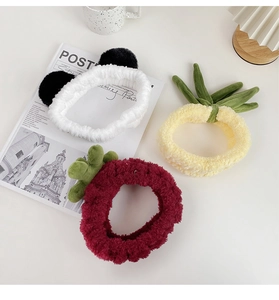 Detailed view of plush panda, pineapple, and strawberry headbands for skincare routine
