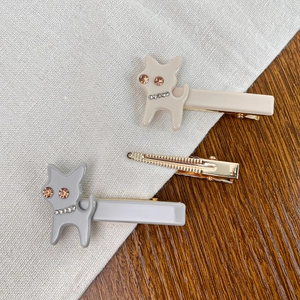 Barrettes à cheveux chat avec strass en beige et gris sur un fond en bois