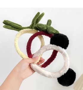 Close-up of three plush panda headbands in cream, yellow, and red for face washing