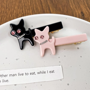 Barrettes chat scintillantes en noir et rose avec détails en strass sur un plat en céramique