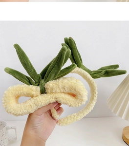 Detail showing plush cream headband with green sprout design and soft velvet texture