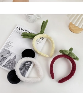 Detailed close-up of plush panda and fruit headbands on a clean white desk setup