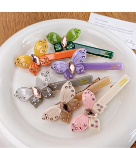Detailed view of handmade acetate butterfly hair clips with crystals and golden branding