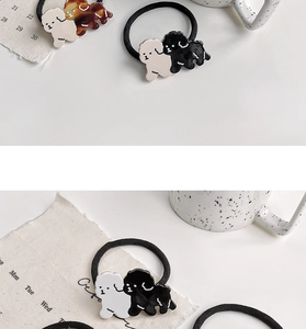 Detailed view of cute acetate dog hair ties in white and black on a white table