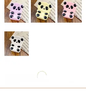 Detailansicht niedlicher Panda-Haarklammern in Pink Gelb und Creme auf Holzoberfläche