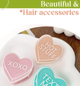 Gros plan de pinces à cheveux en acrylique en forme de cœur rose, orange et bleu avec XOXO