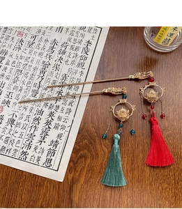 Detail of vintage Chinese lantern hair sticks with red and green tassels on wood