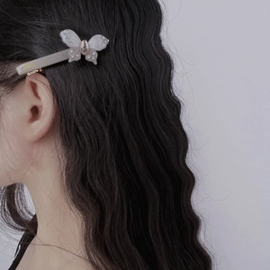 Elegant butterfly hair clip with rhinestones worn on black wavy hair for styling