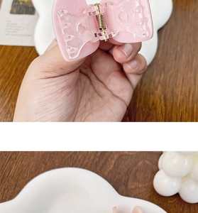 Détail d'une pince à cheveux en acrylique rose en forme de cœur avec ressort doré