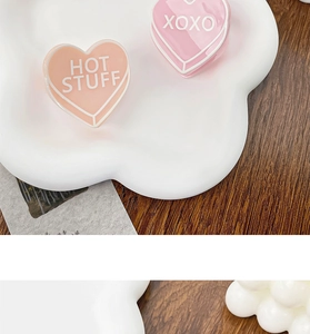 Détail de pinces à cheveux coeur en acrylique rose et orange avec textes HOT STUFF et XOXO