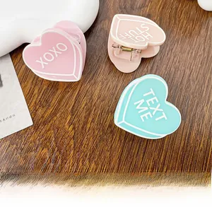Détail de pinces à cheveux mates en forme de cœur rose et vert menthe avec texte XOXO