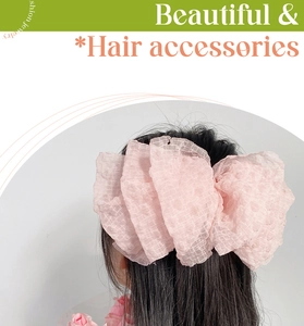 Detail view of large pink seersucker bow hair clip worn by a model from behind