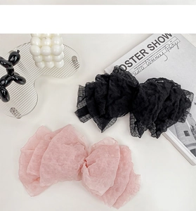 Close-up of oversized seersucker bow hair clips in black and pink with textured grid fabric