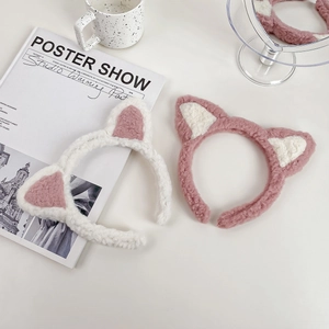 Serre-têtes oreilles de chat en peluche rose et blanche sur une table minimaliste