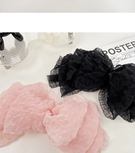 Close-up of pink and black seersucker bow hair clips with delicate mesh texture and layers