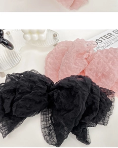 Detail of seersucker bow hair clip showing pink and black fabric textures and mesh edges