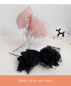 Detail showing pink and black seersucker oversized bow hair clips with polka dot texture
