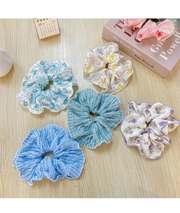 Cinque elastici scrunchie in chiffon a fiori e righe su un tavolo di legno chiaro