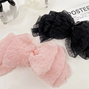 Pink and black seersucker oversized bow hair clips displayed on a stylish glass tray