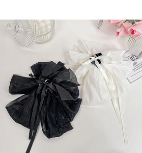 Detail of oversized satin bow hair claw clips in black and white with ribbon streamers