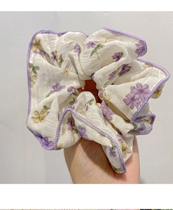 Dettaglio di elastico per capelli floreale con cuciture viola e fiori gialli