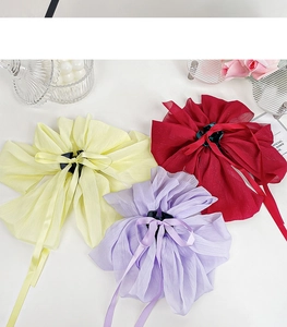 Detailed view of large pleated chiffon bow hair claws in yellow, wine red, and purple