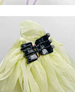 Detail shot of the black acrylic hair claw with a large pale green organza bow ribbon