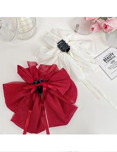 Close-up of elegant burgundy and white satin bow hair clips with long ribbons and rose decor