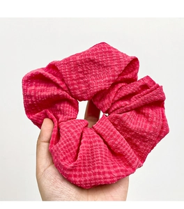 Detailed macro view of magenta checkered fabric texture on a large elastic hair scrunchie