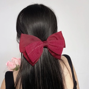 Grande barrette à nœud en satin rouge foncé sur de longs cheveux noirs élégants