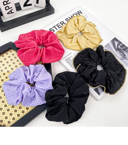 Flat lay of five assorted scrunchies including checkered patterns and gold-threaded edges
