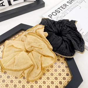 Elegant black and champagne scrunchies with gold thread edging on a vintage background