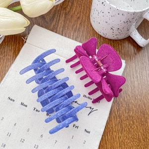 Pinces à cheveux floquées élégantes en violet et rouge rose sur un bureau en bois doux