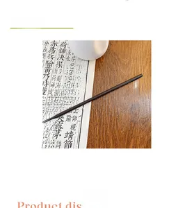 Detail view of a dark wood hair pin with green leaf charms on a calligraphic background