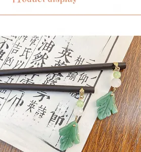 Detail of wooden hair sticks with green leaf pendants on a traditional calligraphy background