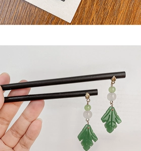 Detailed view of green leaf drop earrings with jade-like beads and gold hooks