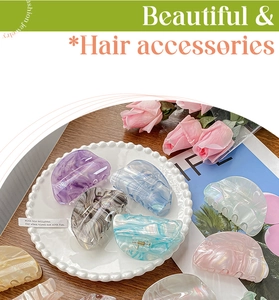 Detail view of acetate claw clips with marble pattern and pearlescent finish on a tray