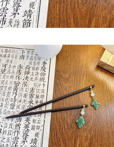 Detail of minimalist wooden hairpins with elegant green jade-like leaf pendants