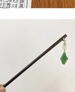 Detail of wooden hairpin with gold leaf accents and green jade-style beaded charms